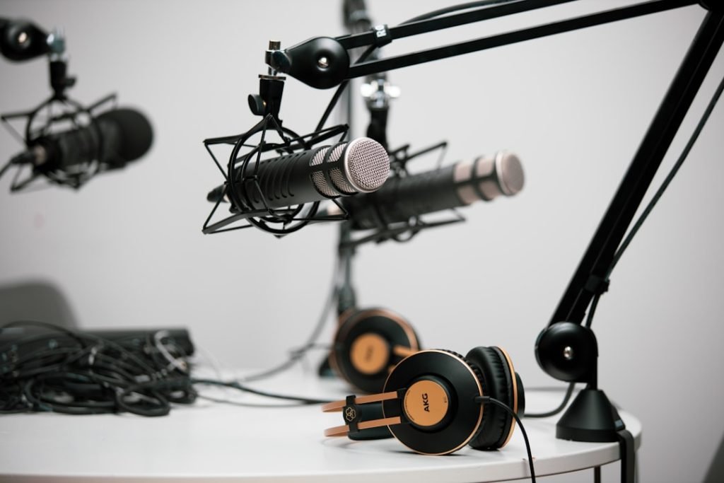 The Art of Drawing Readers In: Your attractive post title goes here Three podcasting microphones on boom arms at a teble with headphones in shot.